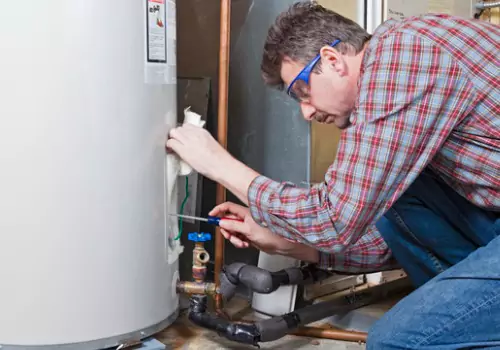 A plumber is seen working on a water heater. Reading Plumbing offers Water Heater Repair in Morton IL.