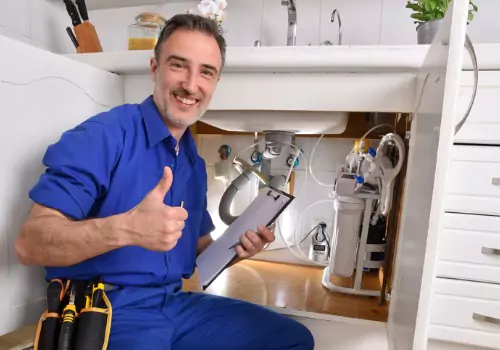 A plumber is seen working under a sink. Reading Plumbing offers plumbing services near you, in Peoria IL.