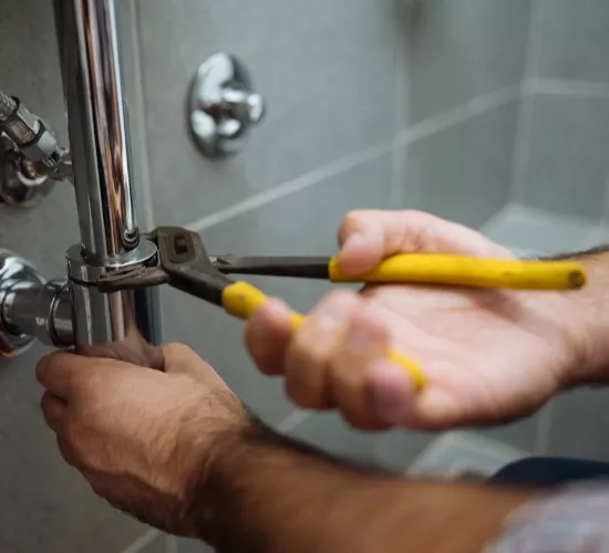 A plumber works on a pipe in one of a home’s bathrooms