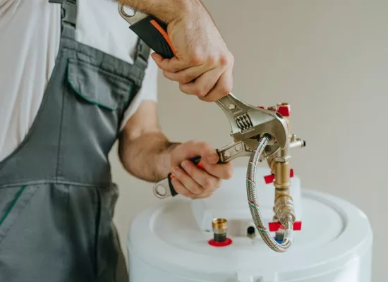 A team member from Reading Plumbing works on a water heater as part of the plumbing services they have to offer.