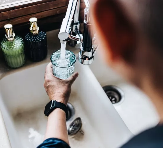 A man fills a water glass with fresh water after installing a water conditioning system.