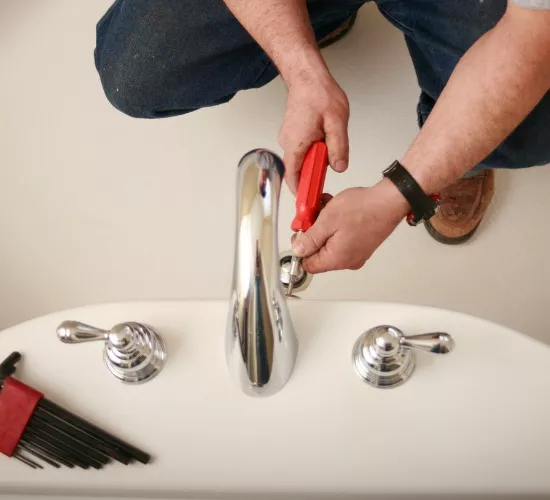 A member of Reading Plumbing works on a bathtub with a screwdriver as part of the drain & fixture repair Reading offers