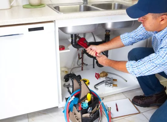 A plumber from Reading Plumbing, a company that offers Central Illinois Plumbing Services, works on a kitchen sink