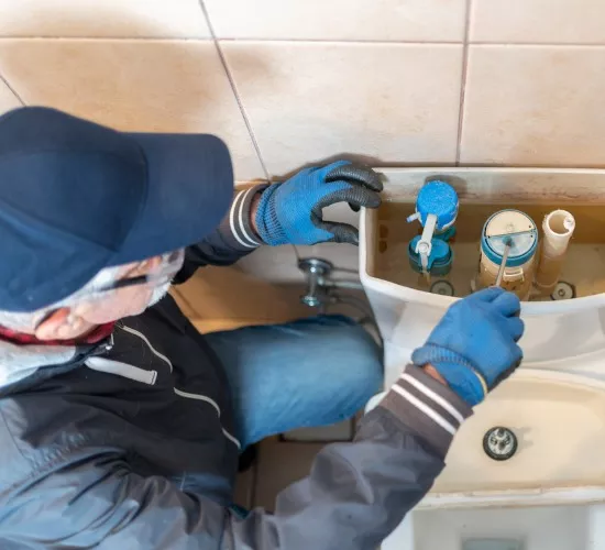 A plumber repairs the toilet in one of a home’s bathrooms, part of Reading Plumbing's bathroom plumbing services