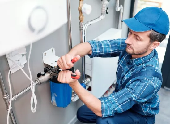 A plumber installs a water filtration system as part of a homeowner’s water conditioning needs.
