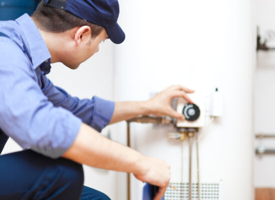 Water Heater Installation Peoria IL, Smiling technician repairing an hot-water heater